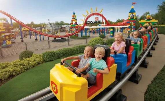 Families enjoying colourful LEGO-themed roller coasters and attractions at LEGOLAND Windsor Resort on a sunny day.
